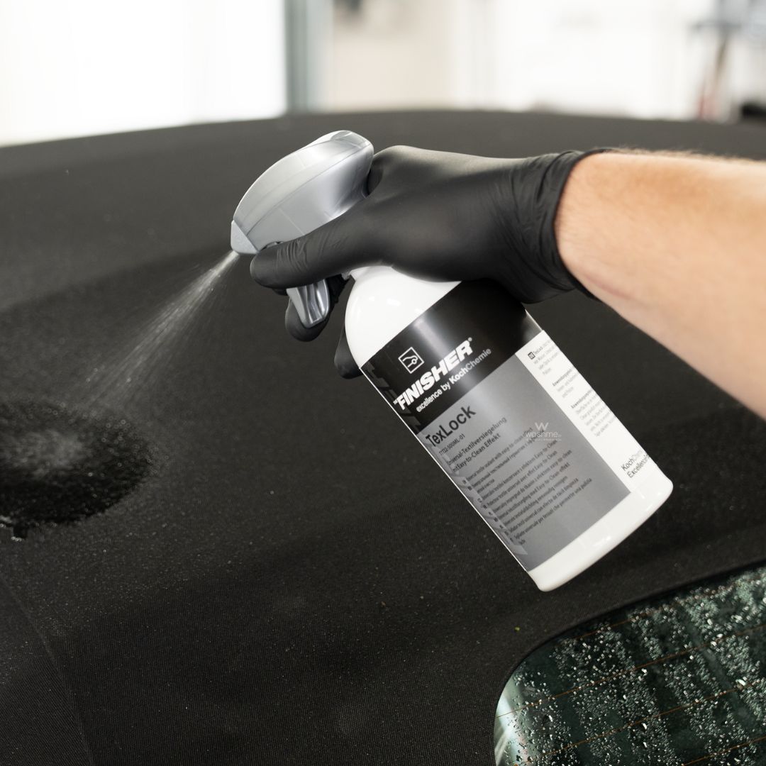 Person applying a Koch Chemie The Finisher TexLock to a black convertible roof surface using a spray bottle.