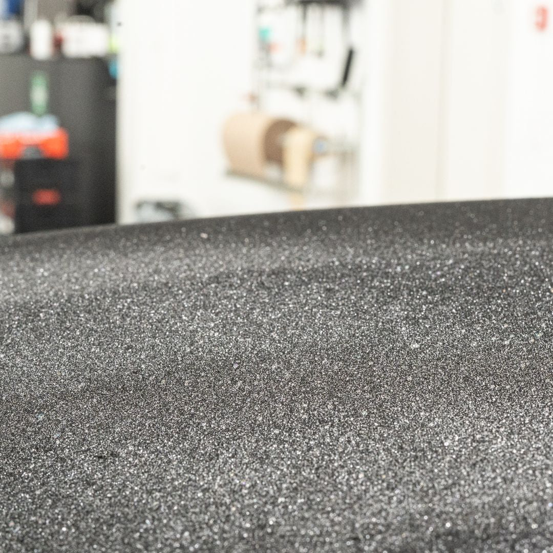Close-up of textured black surface with blurred indoor background