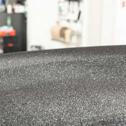 Close-up of textured black surface with blurred indoor background