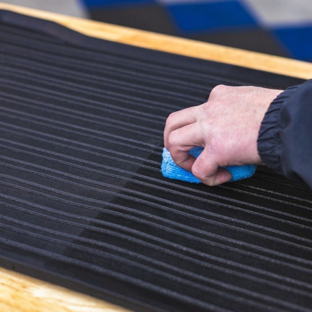 Person cleaning a black surface with a blue cloth