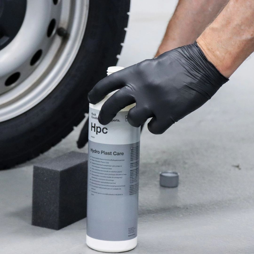 Person holding a bottle of Koch Chemie HPC Hydro Plast Care next to a car tire.