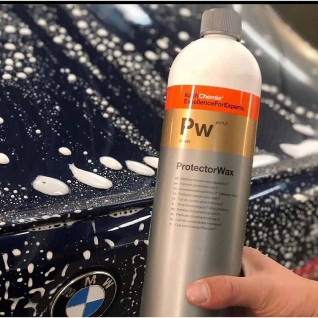 Bottle of Koch Chemie PW Premium Protector Wax held in front of a car with soap suds