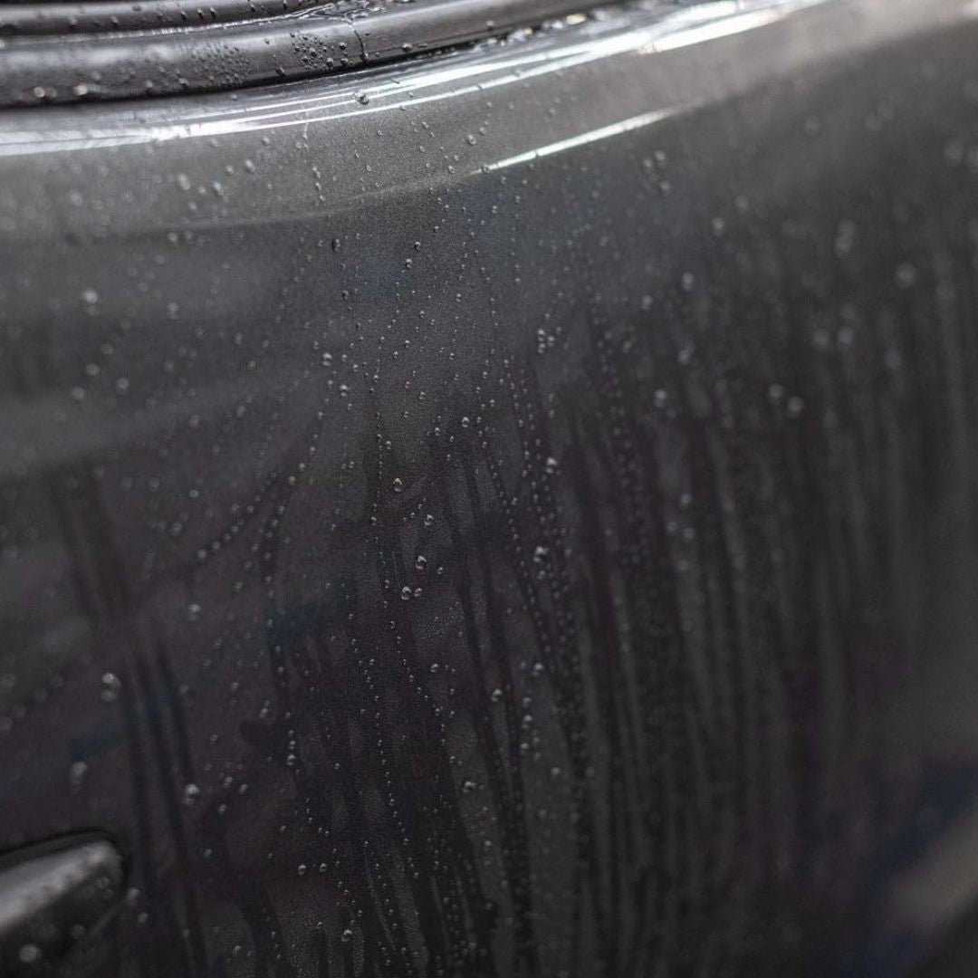 Close-up of a car door with water droplets on a rainy day