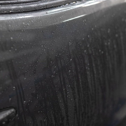 Close-up of a car door with water droplets on a rainy day