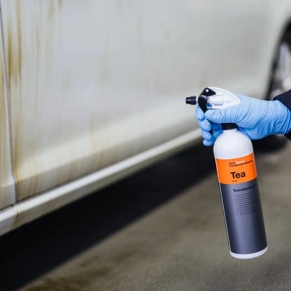 Person spraying Koch Chemie TEA Tar Remover on a vehicle's door that has loads of tar. tar can be seen melting