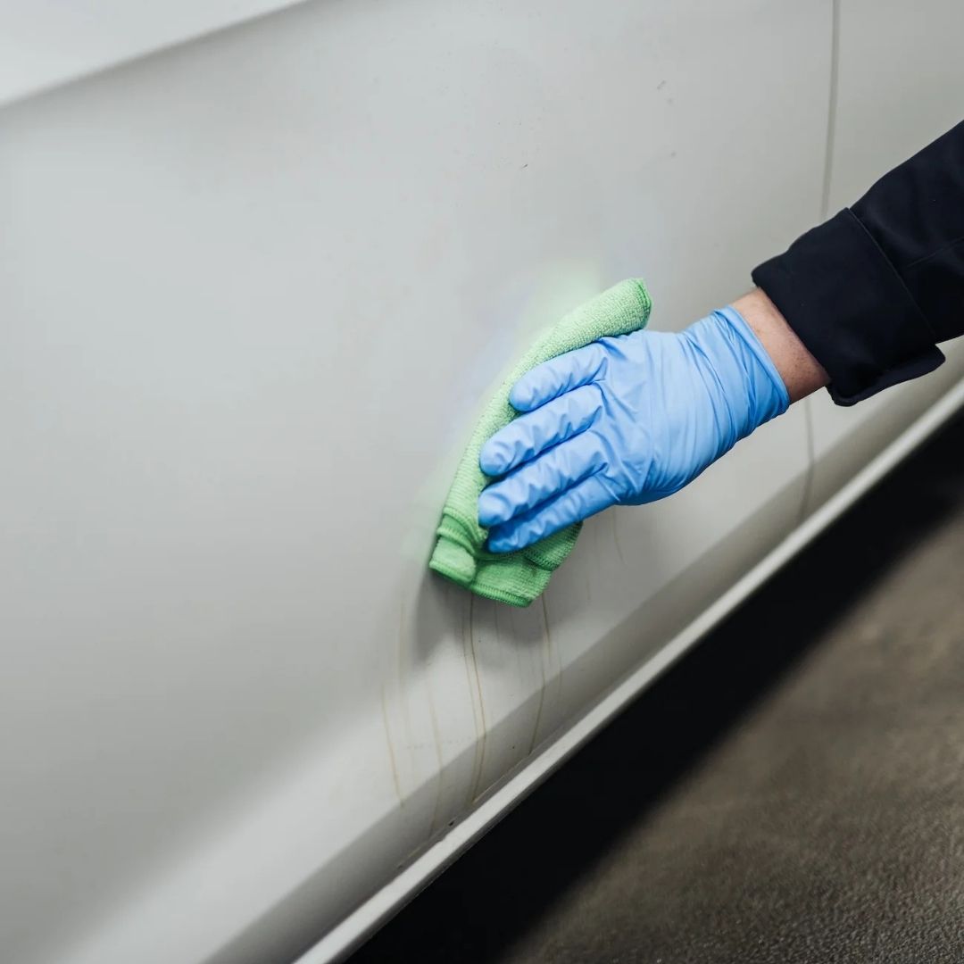 Person cleaning a surface with a green cloth and blue gloves