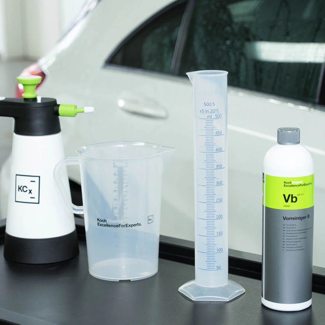 Koch Chemie VB Highly Concentrated Pre-Cleaner products including a spray bottle, measuring cup, and container on a car's hood.
