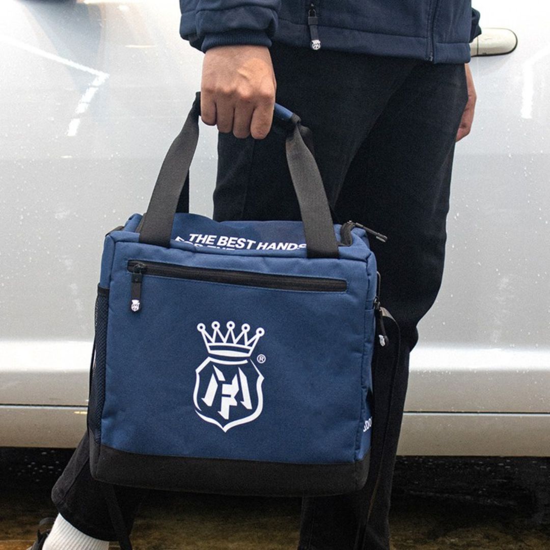 Person holding a blue labocosmetica bag with a logo and text in front of a car.