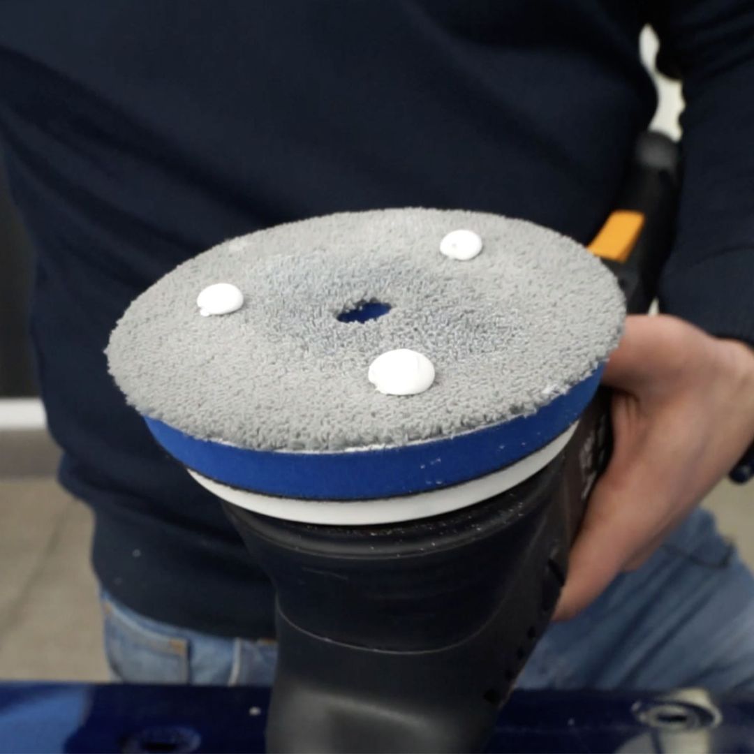 Person holding a hybrid microfibre polishing pad attached to a polisher applying cutting compounds