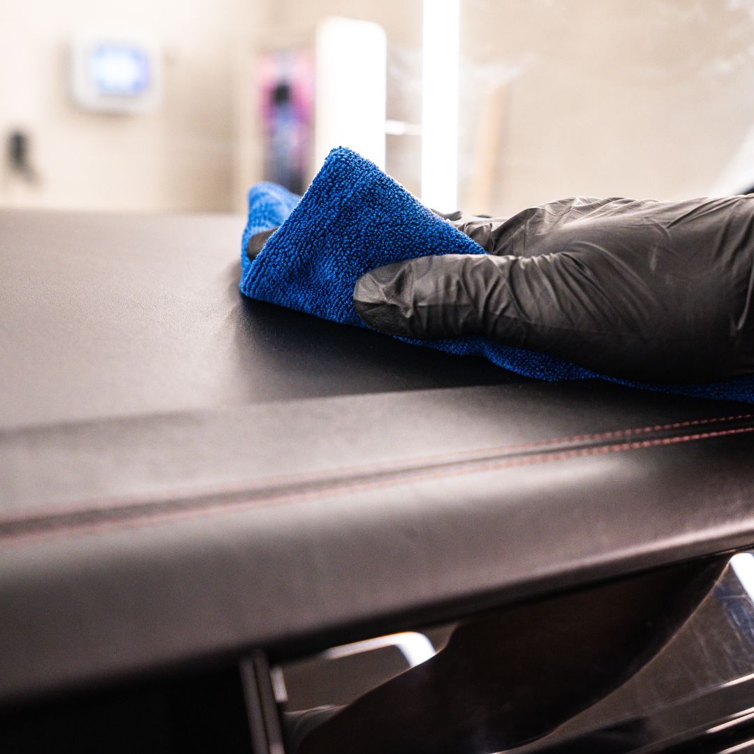 Person cleaning a Porsche dashboard with a blue towel and black glove