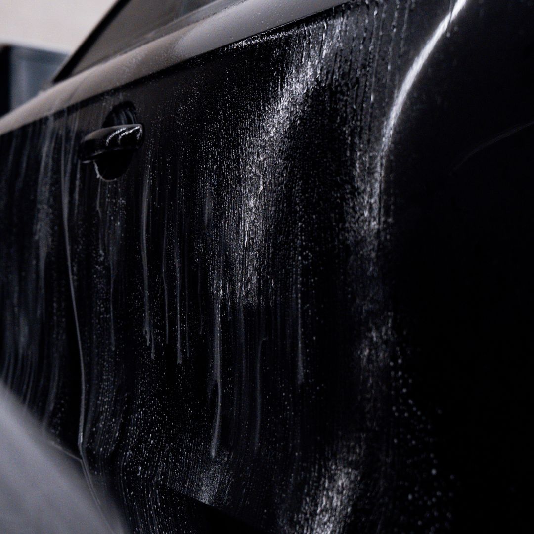 Close-up of a black car with water droplets on the surface