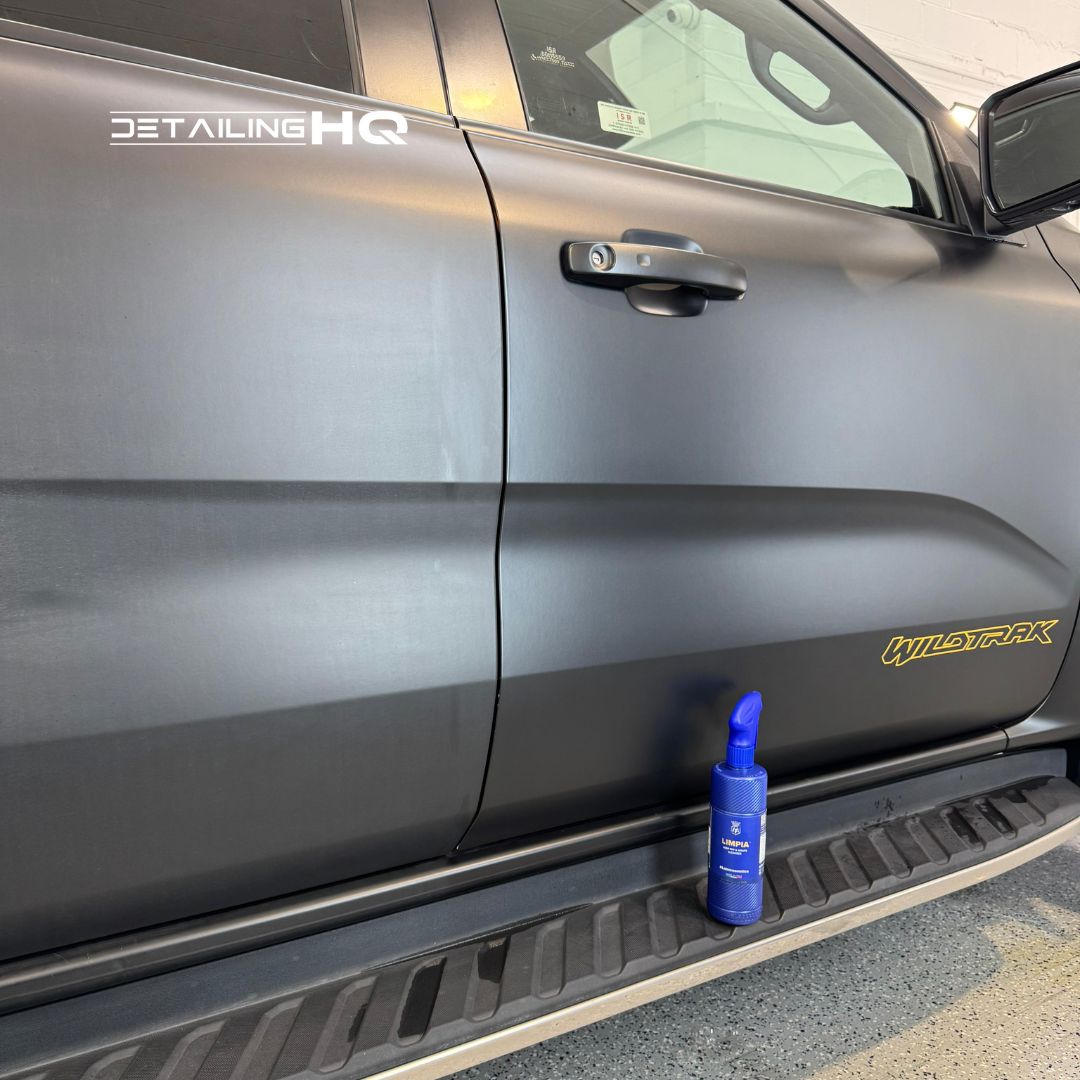 Car door with a blue spray bottle on the step, featuring 'Detailing HQ' branding.
