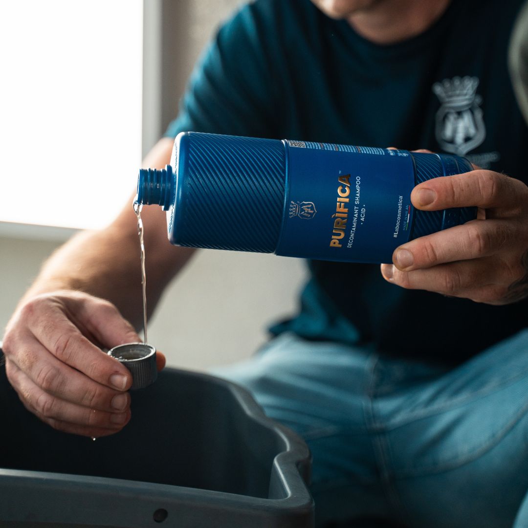 Person pouring Labocosmetica Purifica Acid Shampoo from a bottle into a bucket.