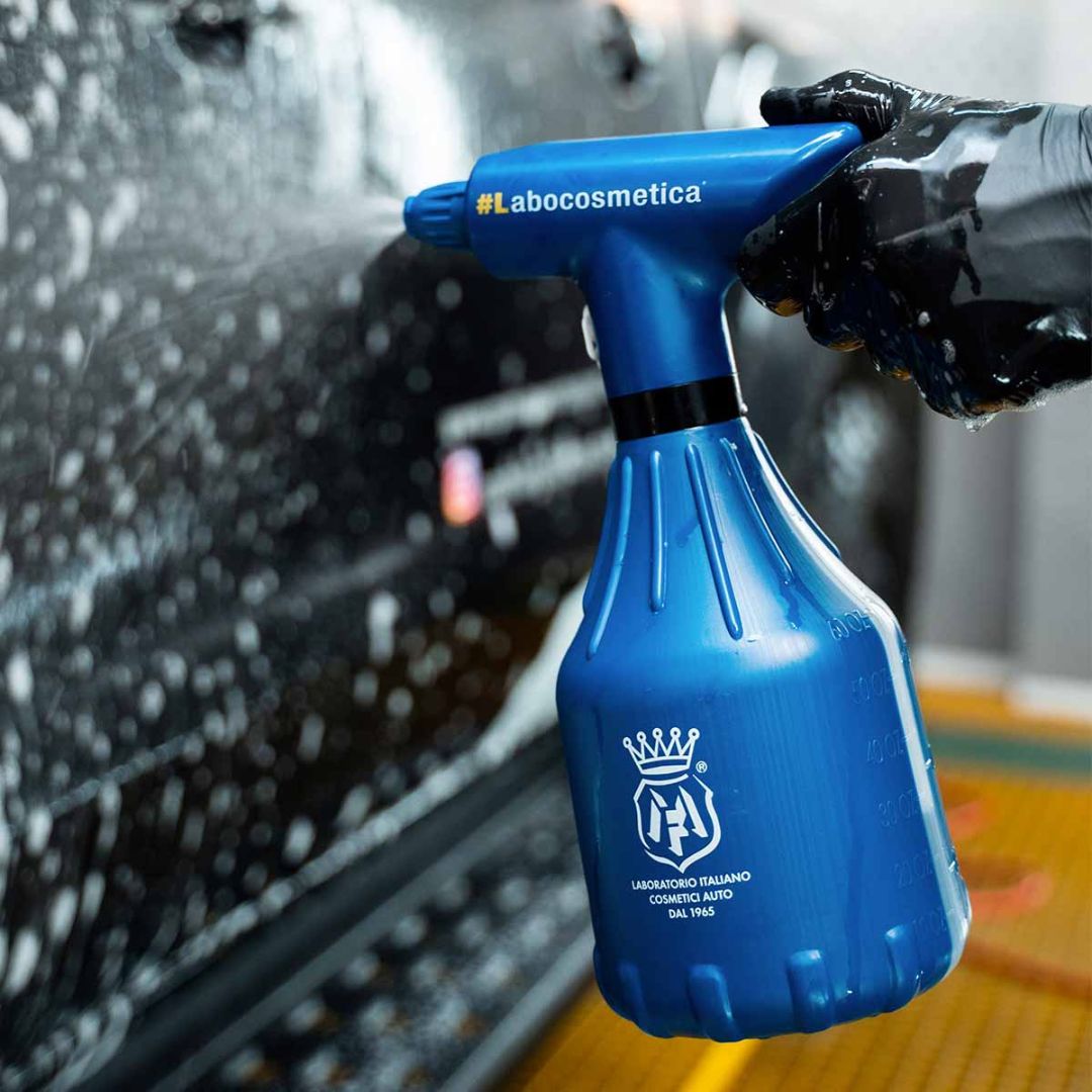 Labocosmetica Spray bottle applying Labocosmetica Purifica on a black car.