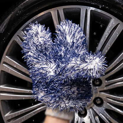 A close-up of a hand washing a silver car wheel with soapy water, wearing a blue and white microfibre cleaning glove by Labocosmetica