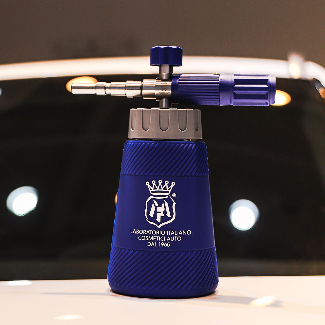 A blue and silver foam cannon attachment for car care products, featuring a textured blue body with the white logo of Labocosmetica Italiano Cosmetics Auto, set against a dark, blurred background with bokeh lights.
