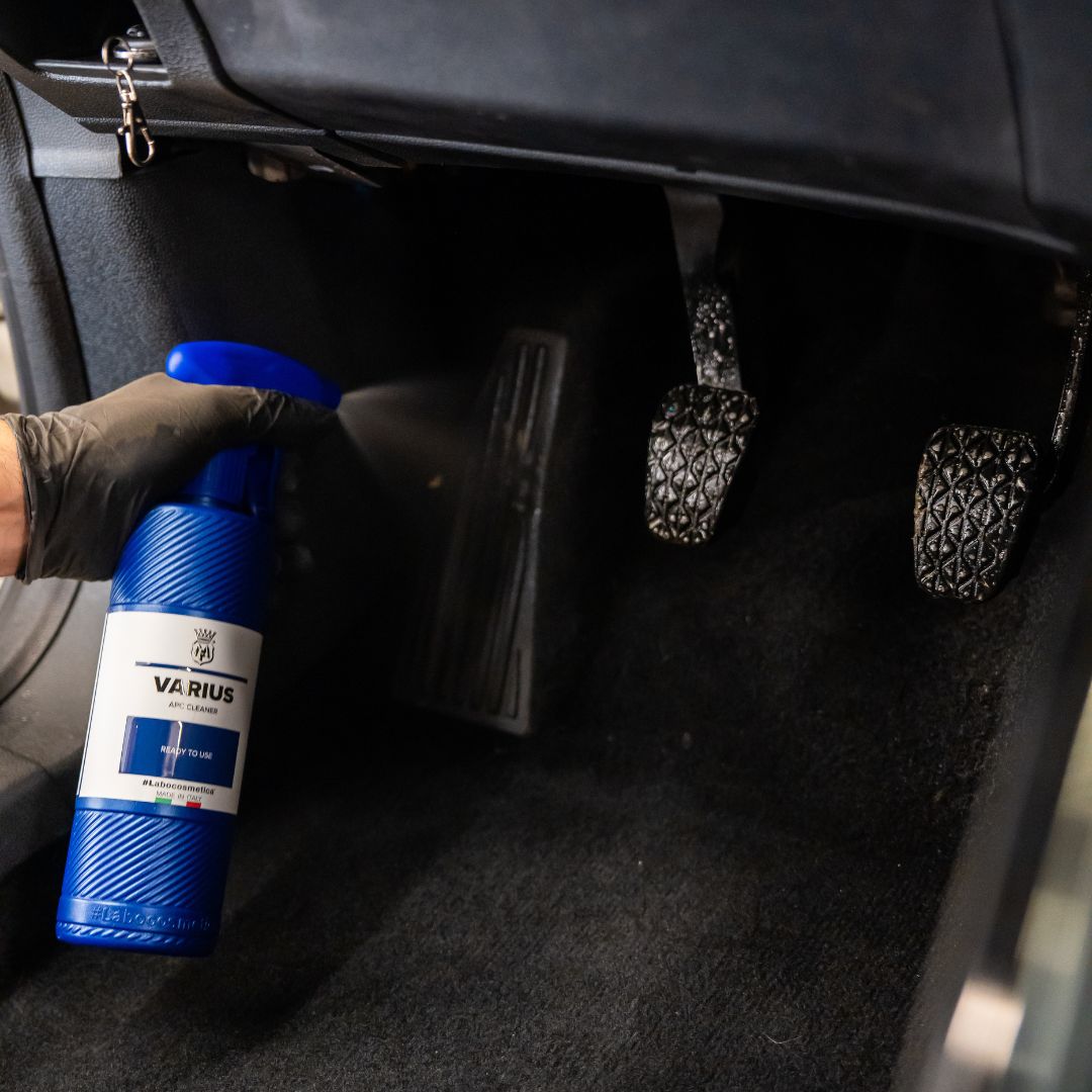 Person holding a blue bottle labeled 'VARIUS' inside a car.