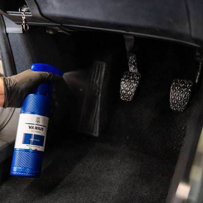 Person holding a blue bottle labeled 'VARIUS' inside a car.