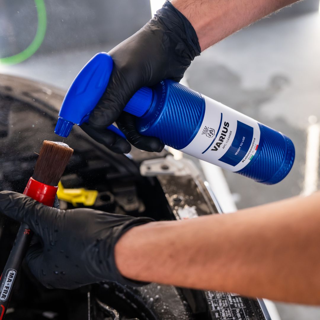 Person using a blue can of Labocosmetica Varius APC on a car engine with gloves on.