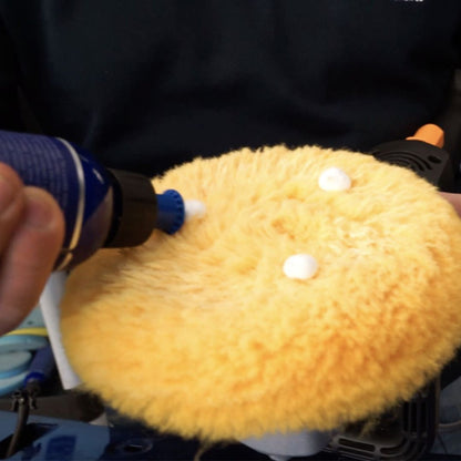 Person applying polishing compound in a blue bottle to a golden wool pad from Labocosmetica