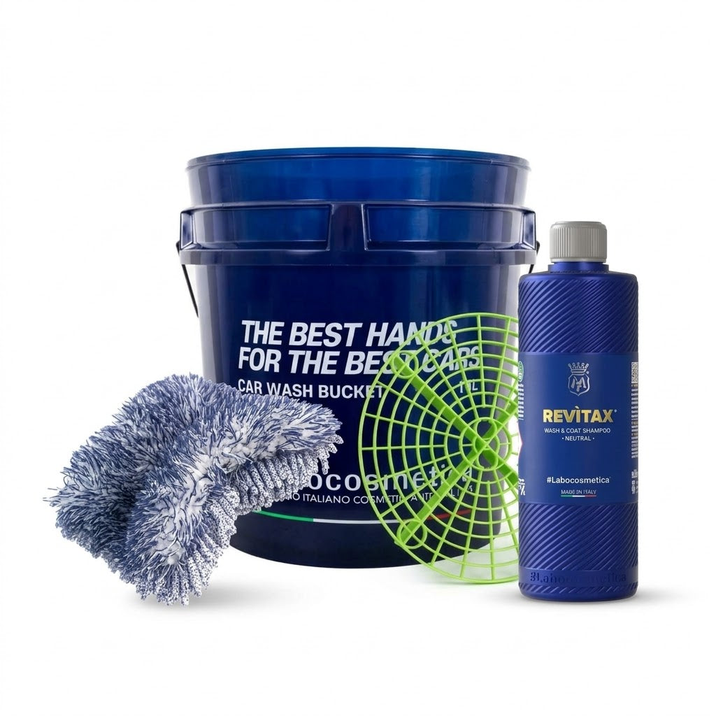 A car wash bucket kit on a white background, featuring a large blue bucket, a smaller blue bottle labeled Labocosmetica REVITAX, a green grit guard, and a blue-and-white microfibre wash mitt.