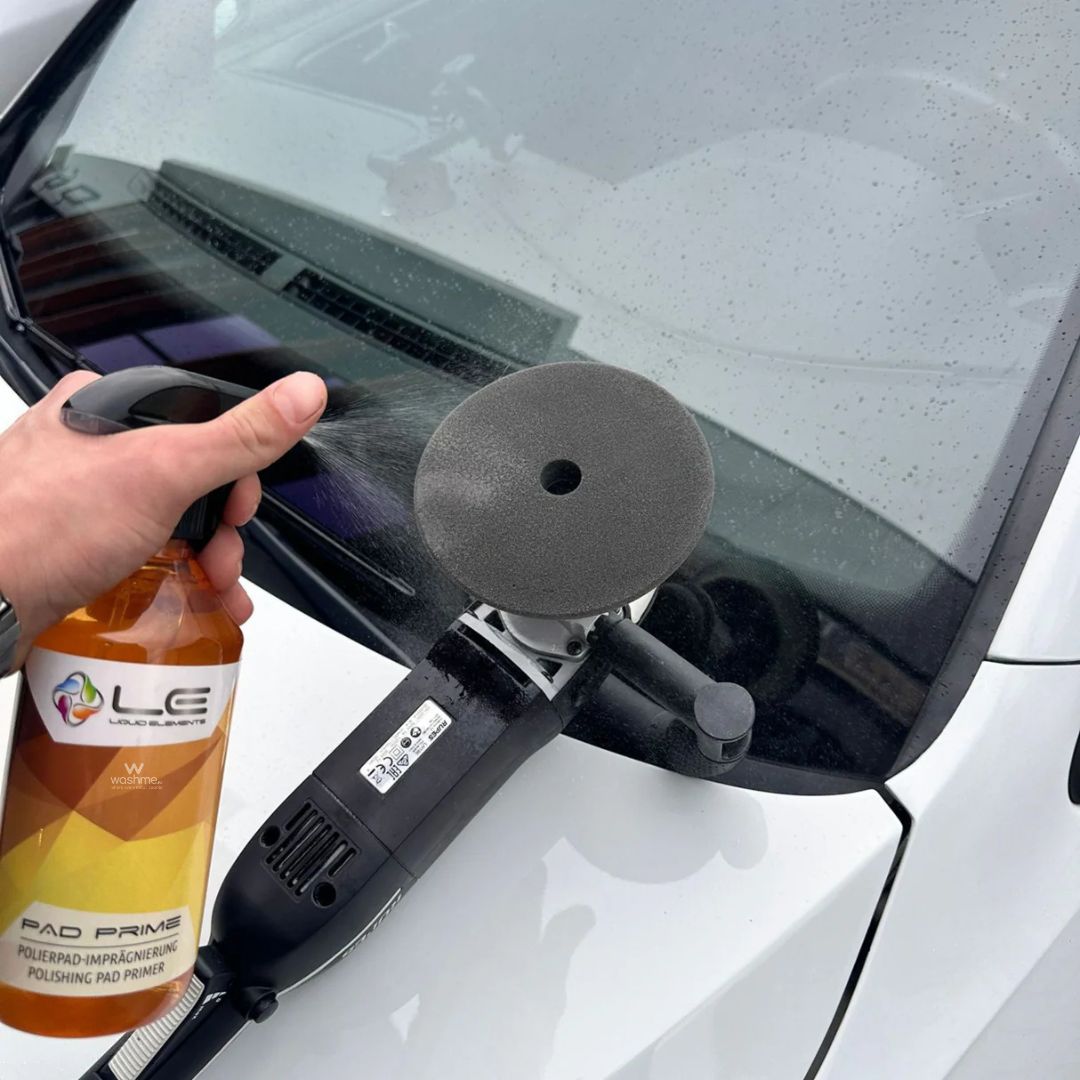 Person using a car detailing tool on a car window with a bottle of LE Pad Prime in the foreground.