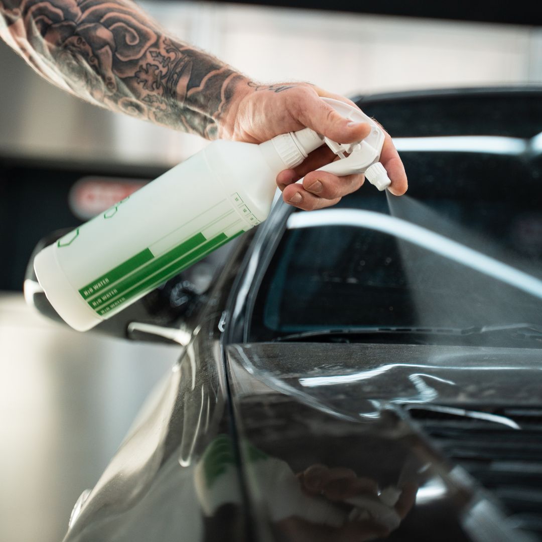 Person cleaning a car window with a spray bottle