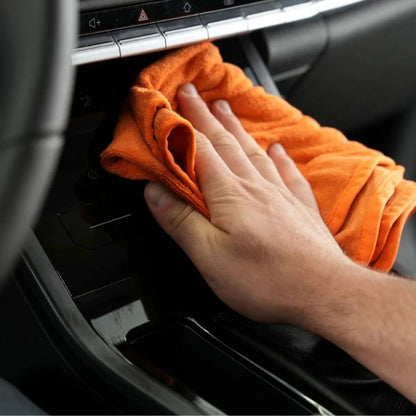 Maniac Interior Quick Detailer sprayed on an orange microfibre cloth cleaning car centre console