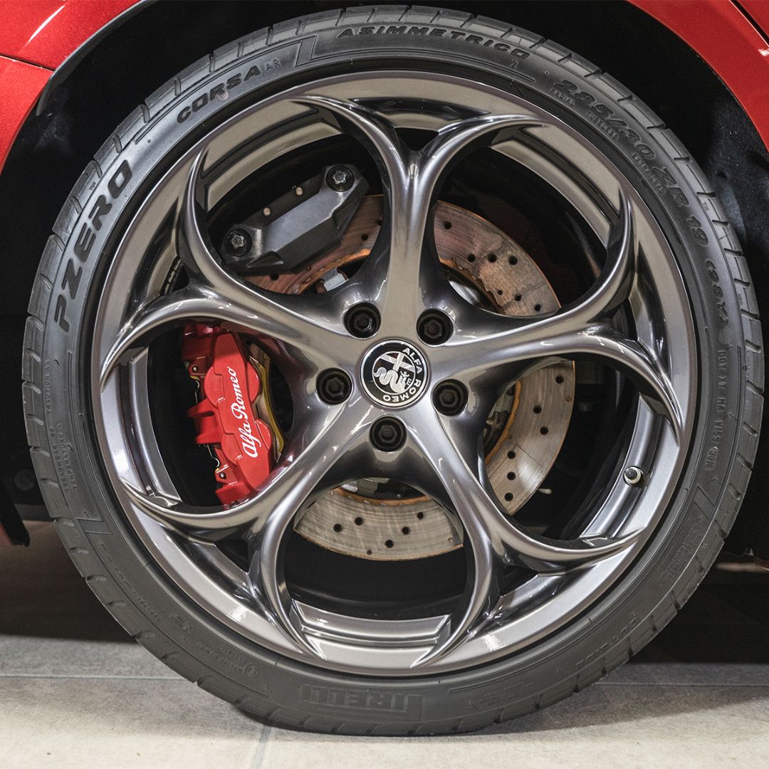 Close-up of a car wheel with Pirelli tire and Alfa Romeo logo.