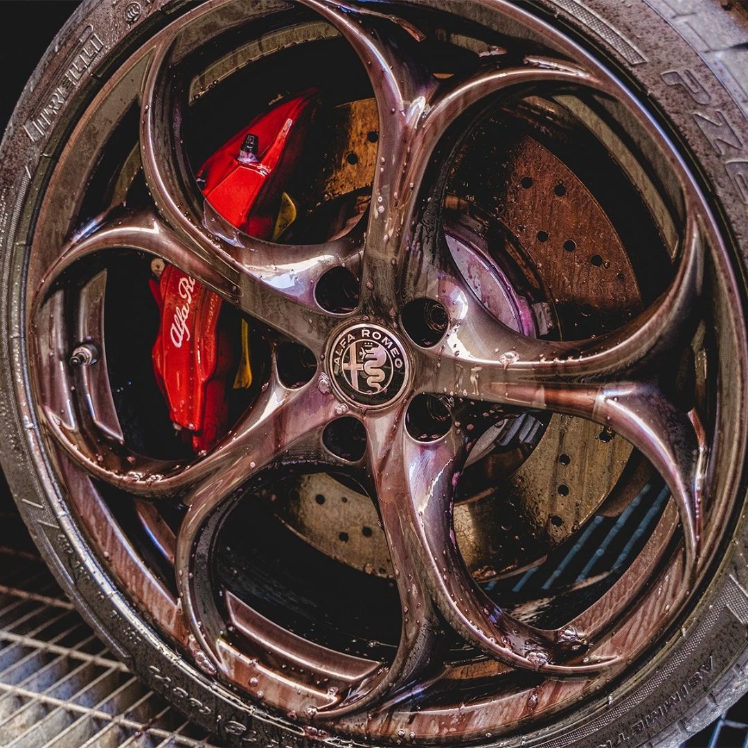 Close-up of an Alfa Romeo wheel with a shiny alloy rim and red brake caliper.