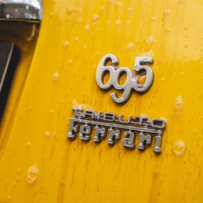 Close-up of a Ferrari Tributo for Fiat 500 Abart 696 on a yellow car with fallout remover droplets