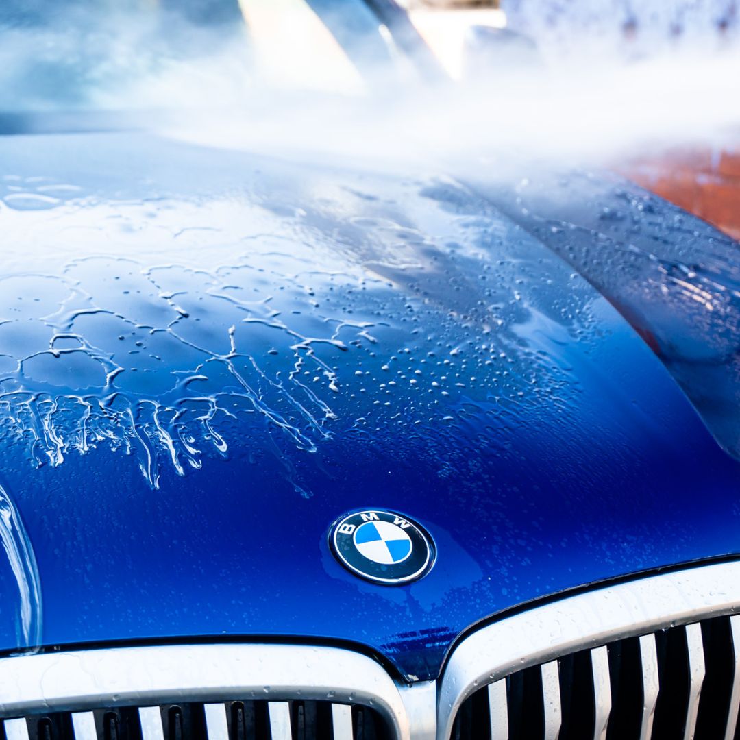 Close-up of a blue BMW car with water droplets on the hood.