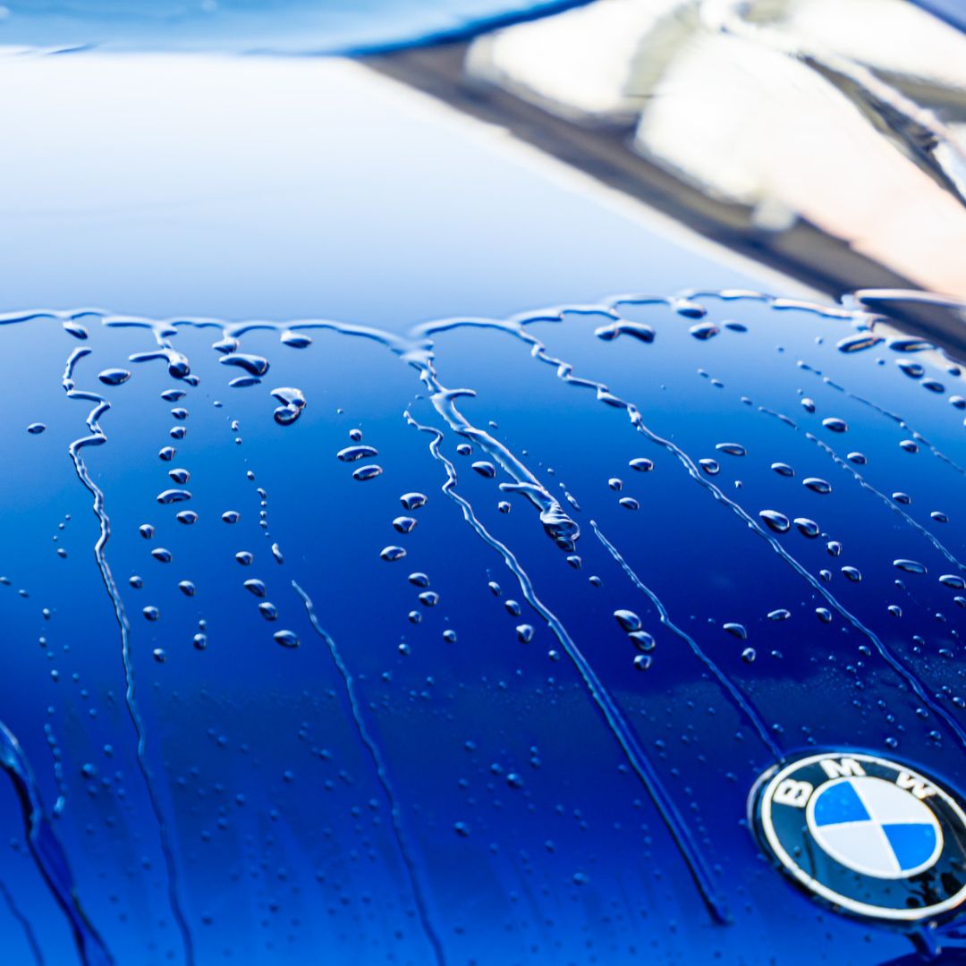 Close-up of a blue BMW car with water droplets on the surface.