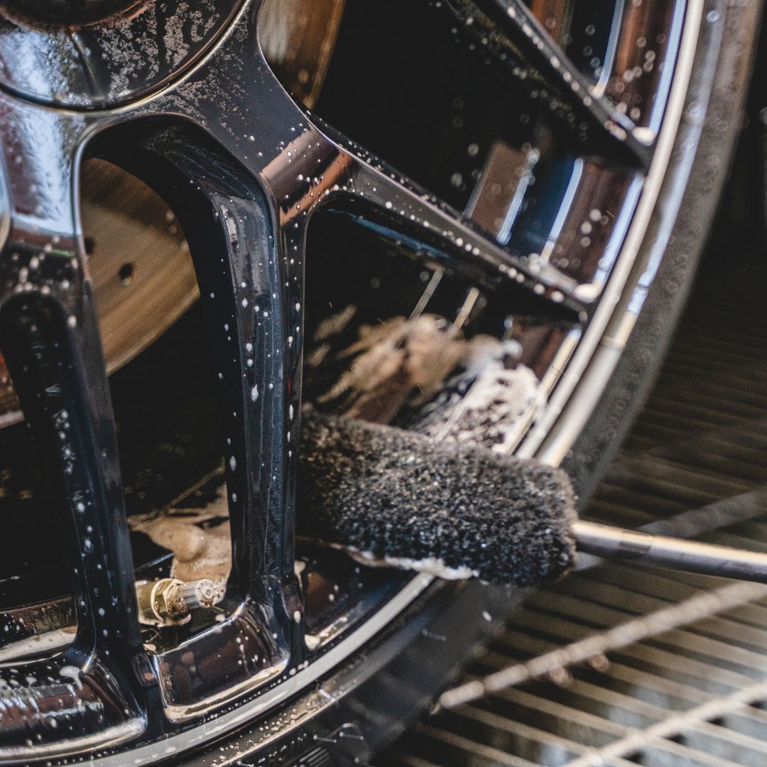 Close-up of a car wheel with a cleaning brush on a metal surface
