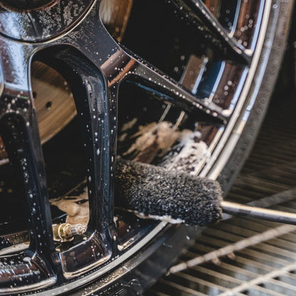 Close-up of a car wheel with a cleaning brush on a metal surface