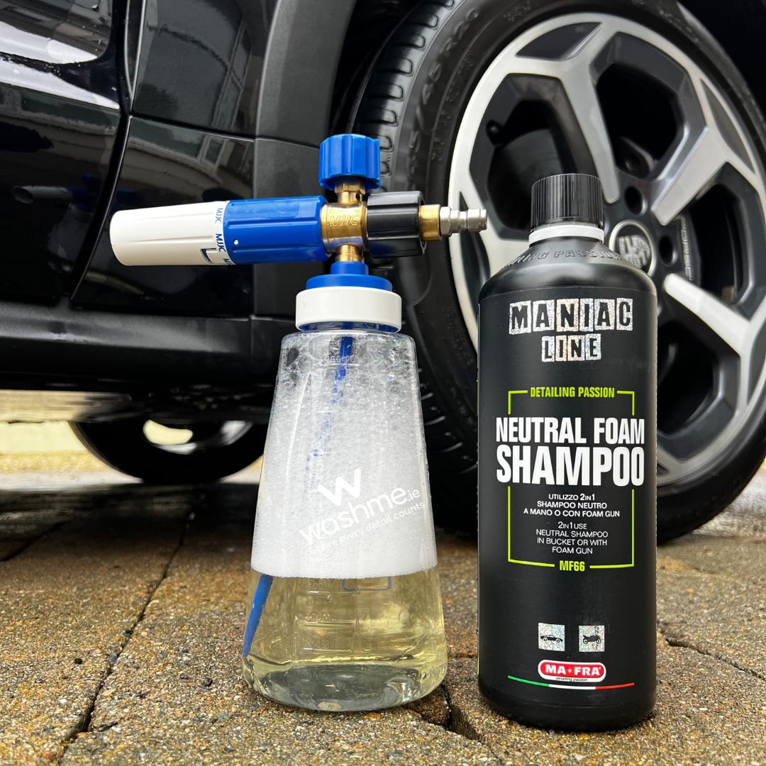 Car cleaning equipment with a bottle of Maniac Line Neutral Foam Shampoo next to a car wheel.