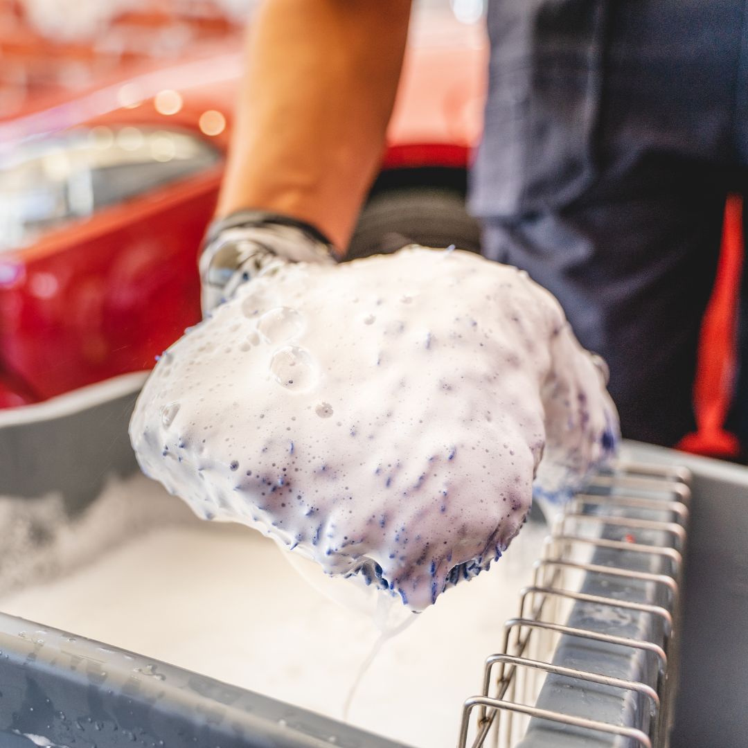 Person holding a mitt with foaming shampoo