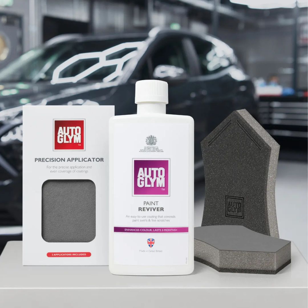 Autoglym car care products including a bottle, applicator, and sponges with a car in the background.