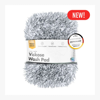 A fluffy gray and white shaggy Viskose wash pad wrapped in a white paper band, with a red 'NEW!' badge and a circular German quality seal on a white background.