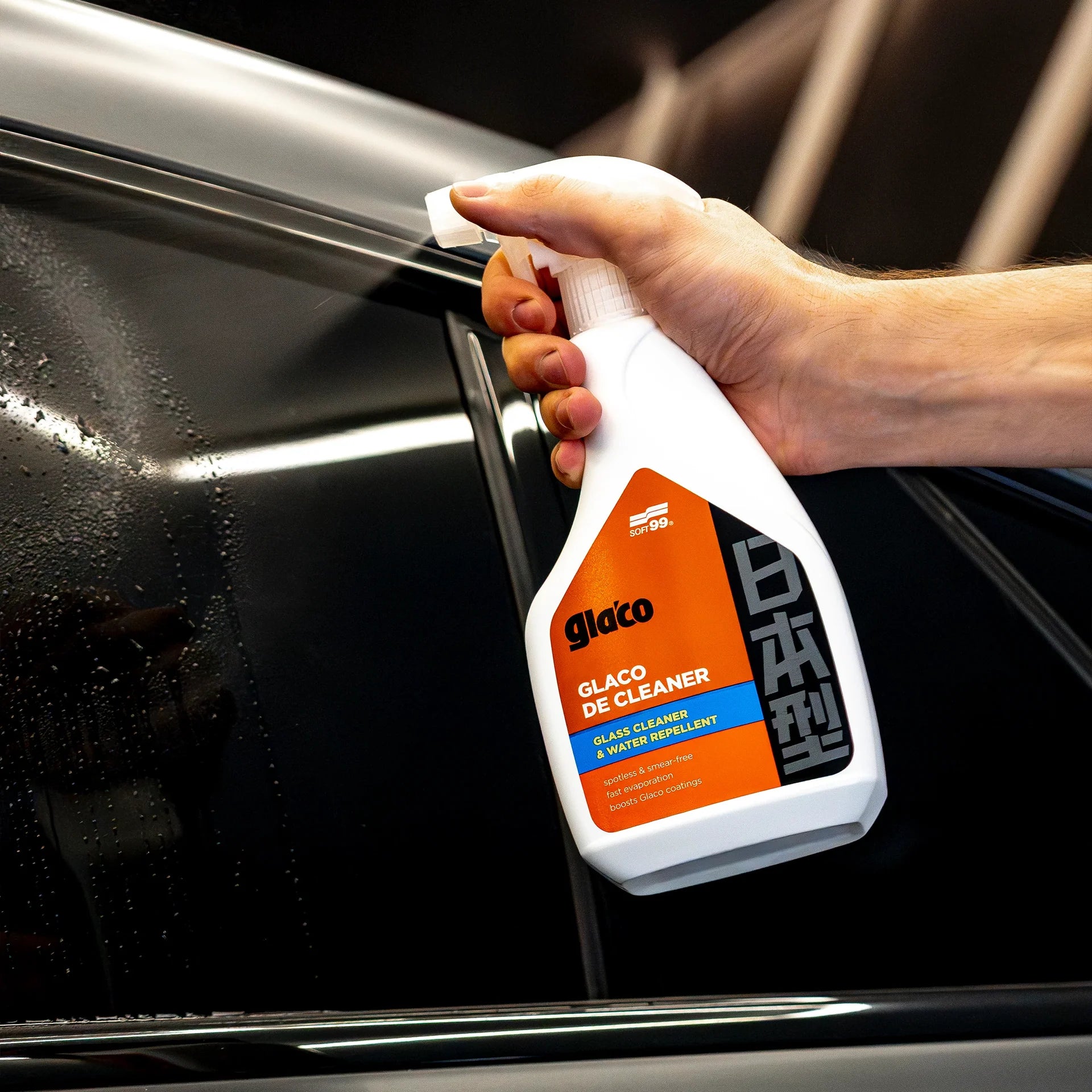 Hand holding a Glaco de Cleaner spray bottle against a car window. New 2026 SOFT99 Glaco De Cleaner Hydrophobic Glass Cleaner 400ml