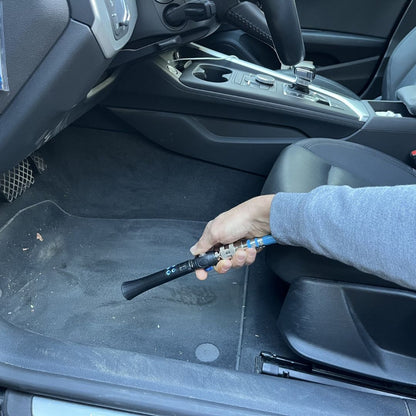 Person holding an air tool inside a car, likely performing maintenance or repair work.