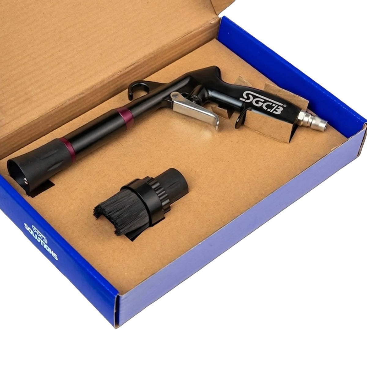 A black and silver SGCB air compressor pistol with its black brush attachment, presented inside an open blue and brown cardboard box on a white background.