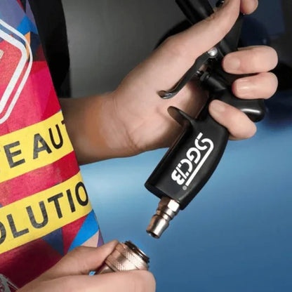 A close-up of a person's hands holding a black SGCB Air gun and connecting a metal hose adapter, with a colourful shirt visible in the background.