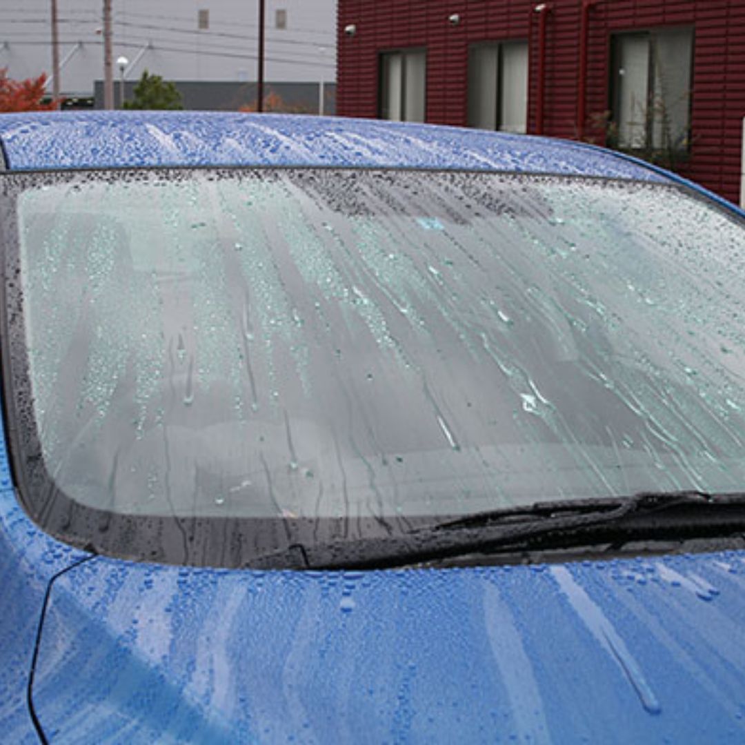 Car windshield with water droplets and a blurred background