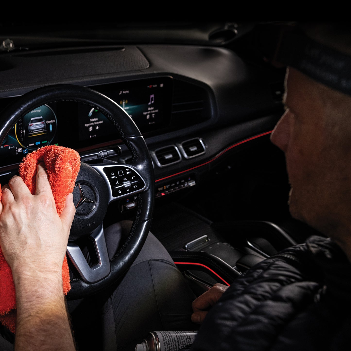Scangrip I-Match 4 Person cleaning a car's dashboard with a red cloth inside a vehicle.