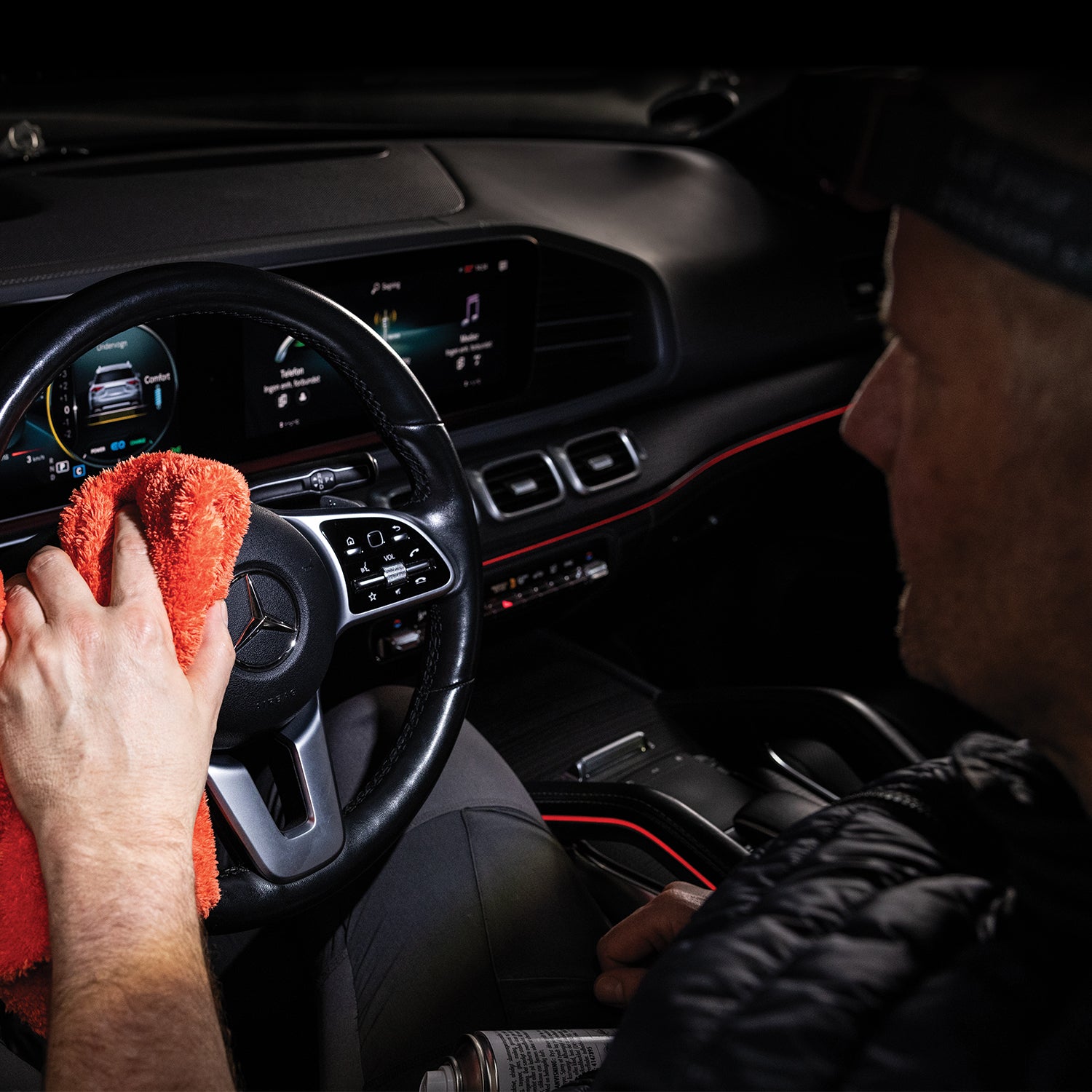 Scangrip I-Match 4 Person cleaning a car's dashboard with a red cloth inside a vehicle.