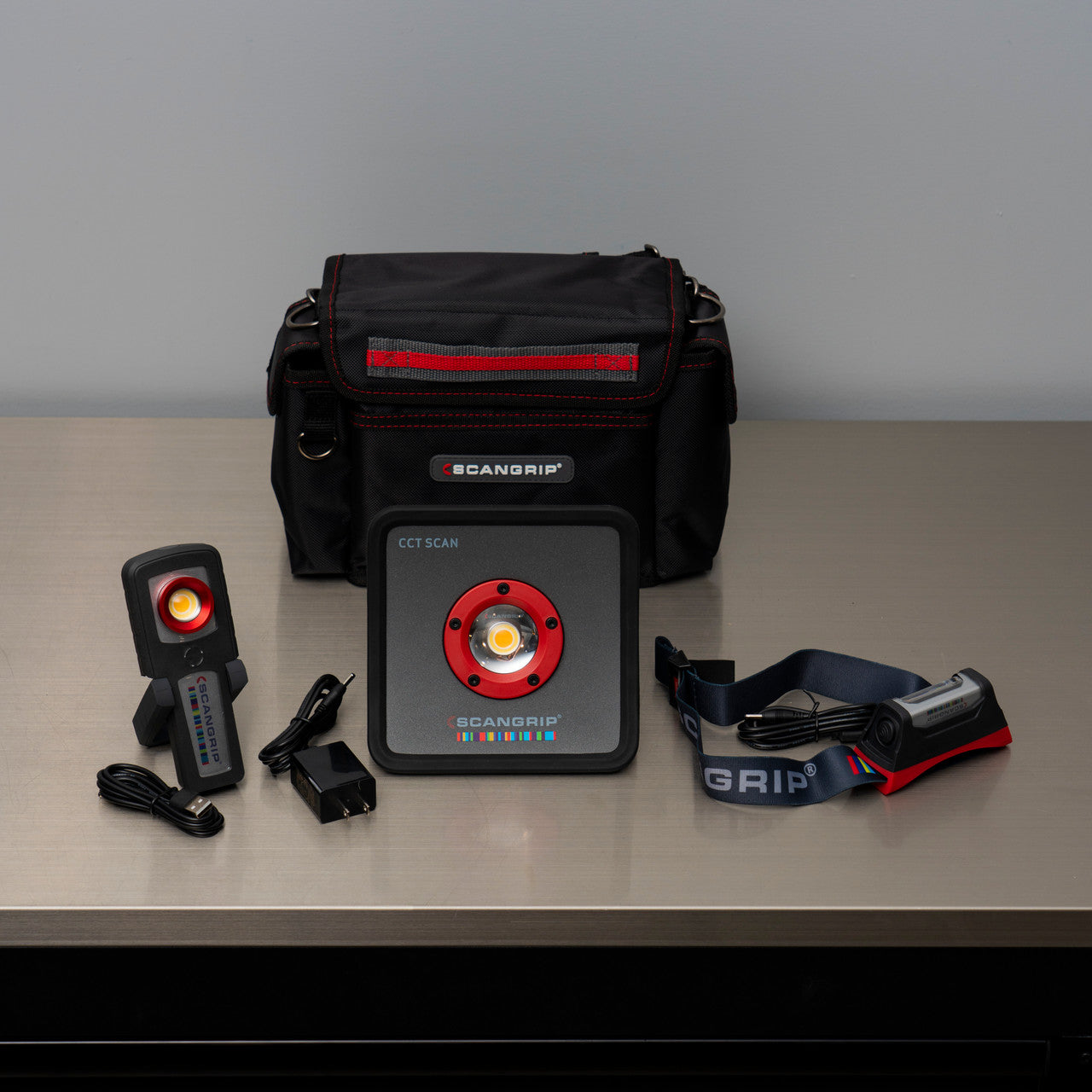 Scangrip equipment including a scanner, power adapter, and carrying case on a gray surface.