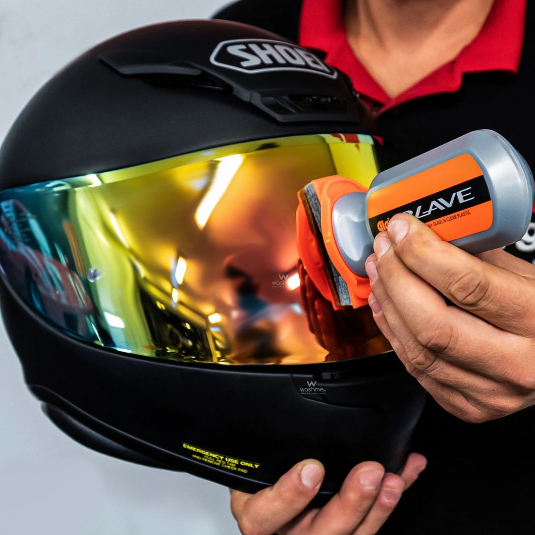 Person using Soft99 Glaco Blave - Glass & Plastic Water Repellent 70ml on a motorcycle helmet with reflective visor.
