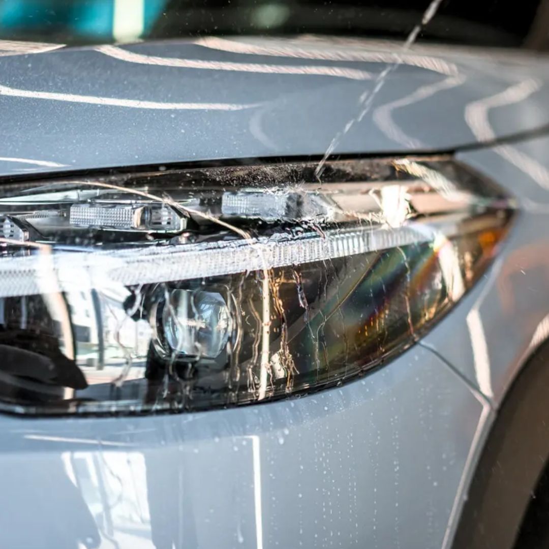 Close-up of a car headlight with visible water beading and hydrophobic capabilities from Soft99 Glaco Blave - Glass & Plastic Water Repellent 70ml