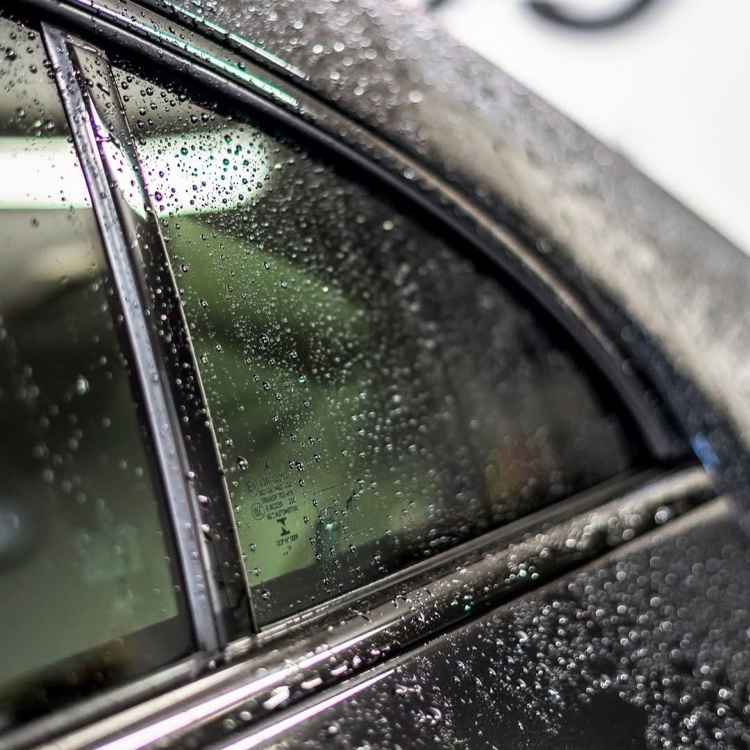 Close-up of a car window with water droplets on a rainy day